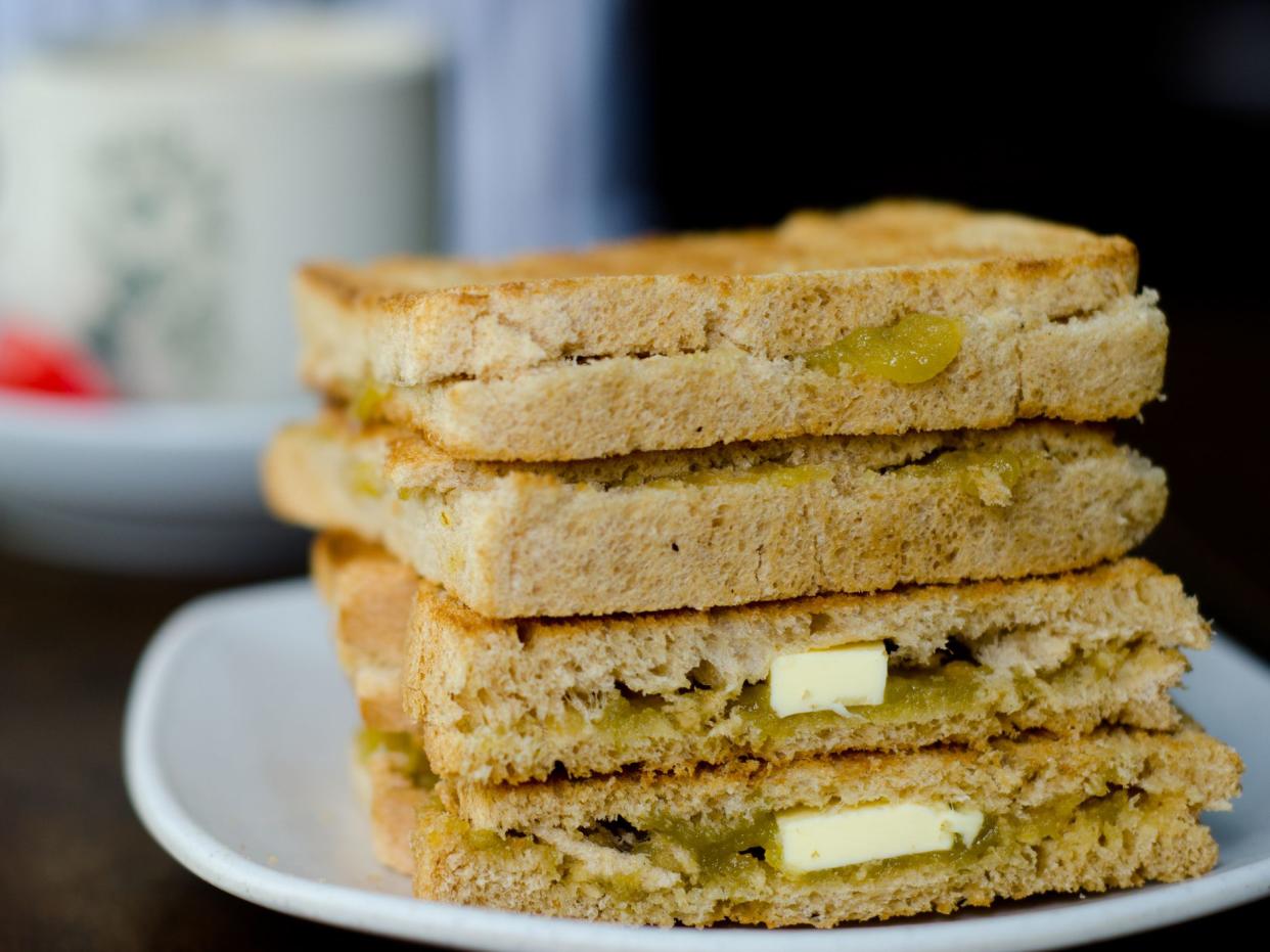 Toast with kaya and butter on a plate with coffee in the background