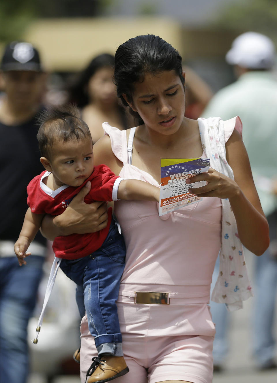 A Venezuelan woman with a baby reads a flyer, given to her by Venezuelan politicians in exile, inviting people to come out to the streets on Feb. 23 to support the planned aid delivery to Venezuela, in La Parada, on the border with Venezuela, Colombia, Sunday, Feb. 17, 2019. As part of U.S. humanitarian aid to Venezuela, Sen. Marco Rubio, R-Fla, is visiting the area where the medical supplies, medicine and food aid is stored before it it expected to be taken across the border on Feb. 23. (AP Photo/Fernando Vergara)