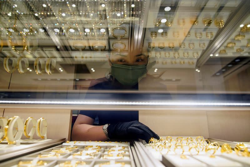 FILE PHOTO: A salesperson poses with gold jewellery at jeweller Chow Tai Fook’s retail store in Shanghai