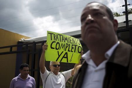 A protester holds a placard which reads "Full treatment now!" during a gathering in demand for medicines in Caracas, Venezuela August 27, 2015. REUTERS/Marco Bello