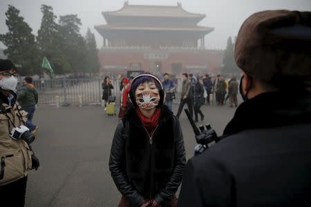 A girl wearing a protective mask talks to a policeman near the Forbidden City on an extremely polluted day as hazardous, choking smog continues to blanket Beijing, China December 1, 2015. REUTERS/Damir Sagolj