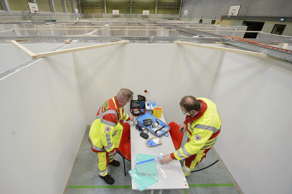 The two emergency paramedics Matthias Gebhardt, left, and Mathias Haas, right, unpack a diagnostic bag in a vaccination center in the sports hall of a school in Eschwege, Germany, Tuesday, Dec. 1, 2020. The German government is preparing to roll out a nationwide coronavirus vaccination program. (Sven Pfoertner/dpa via AP)