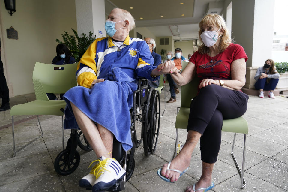 Residents Ken Fishman, 81, left, and Esther Wallach, 82, hold hands as they wait in line for the Pfizer-BioNTech COVID-19 vaccine at the The Palace assisted living facility, Tuesday, Jan. 12, 2021, in Coral Gables, Fla. (AP Photo/Lynne Sladky)