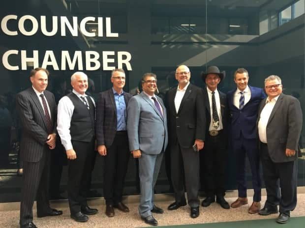 Representatives from the three groups behind the Flames arena deal pose for a photo after it was approved by council. From left: Barry Munro, who handled negotiations for the city; Coun. Ward Sutherland; John Bean of CSEC; Mayor Naheed Nenshi; Ken King of CSEC; Stampede CEO Warren Connell; Coun. Jeff Davison; and Coun. Shane Keating.