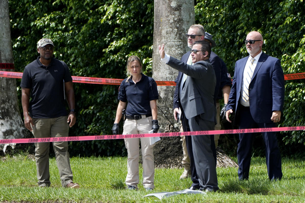 Law enforcement officials standing in an area that has been cordoned off with police tape.