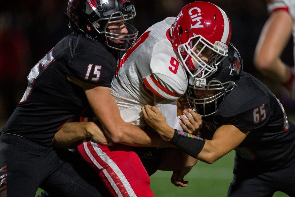 North Posey’s Devin Lintzenich (15) and Zach Blaylock (65) tackle Tell City’s Aiden Ferrand (9) as the North Posey Vikings play the Tell City Marksmen at North Posey High School Friday evening, Sept. 10, 2021. 