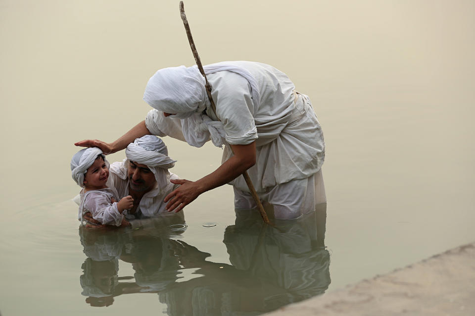 In this Sunday, Oct. 14, 2018 photo, a follower of the obscure and ancient Mandaean faith baptizes a child along a strip of embankment on the Tigris River reserved for them, in Baghdad, Iraq. Iraq’s soaring water pollution is threatening the religious rites of its tight-knit Mandaean community, already devastated by 15 years of war that has also affected the country’s other minority Abrahamic sects. (AP Photo/Hadi Mizban)