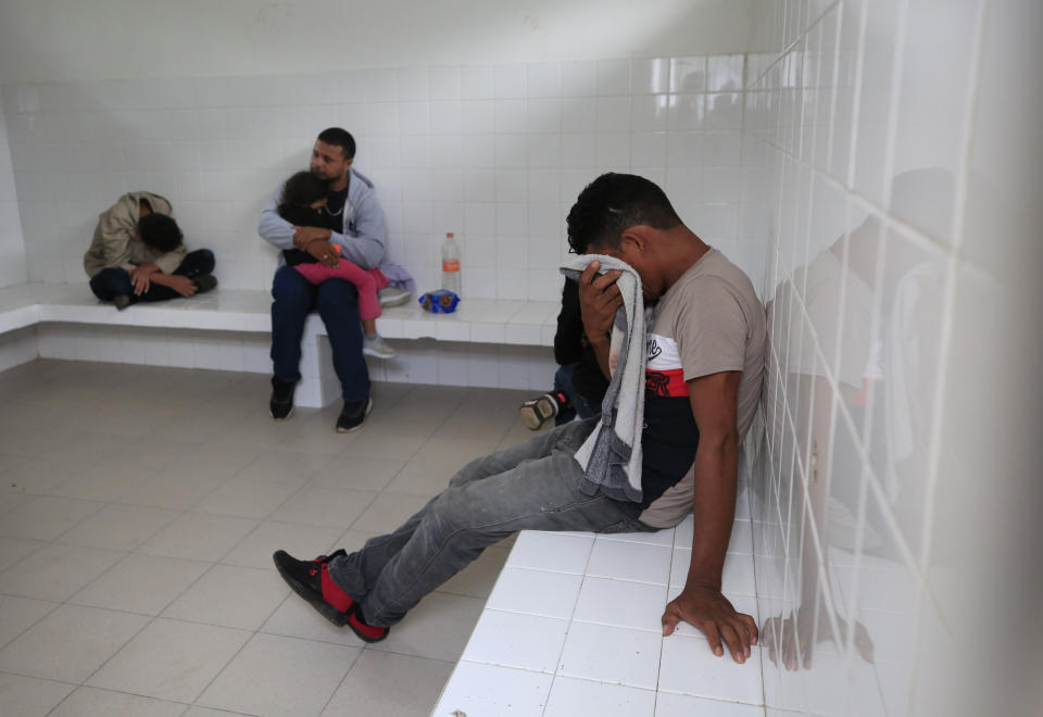 A young man cries as he says that if he gets sent back to Honduras, he will be killed, while sitting with other migrants inside an immigration holding cell after being removed from a bus heading north out of Comitan, Chiapas state, Mexico, Sunday, June 16, 2019. Behind is Honduran migrant Noe, 31, holding his 4-year-old daughter Marlene. Mexican President Andrés Manuel López Obrador said Saturday his country must help Central Americans fleeing poverty and violence, even as it increases security and revisions to deter migrants from passing through Mexico on route to the U.S. (AP Photo/Rebecca Blackwell)