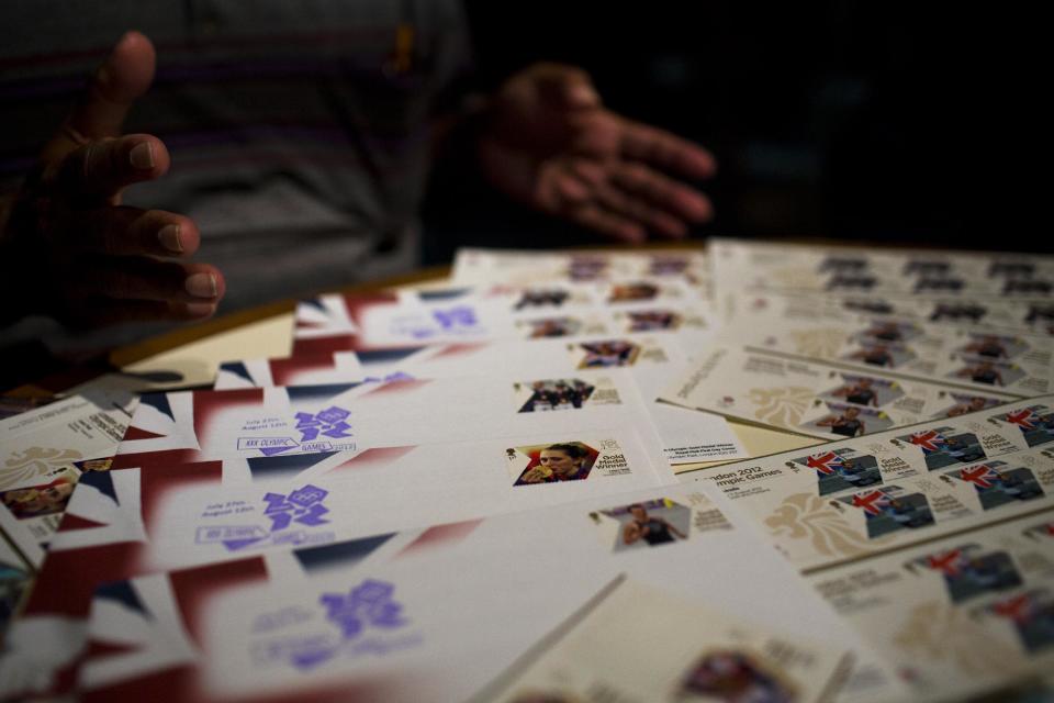 Herman Sanchez gestures towards his collection of stamps during the 2012 Summer Olympics on Wednesday, Aug. 8, 2012, in London. London has been issuing stamps every day with photos of Britain’s gold medallists. (AP Photo/Emilio Morenatti)