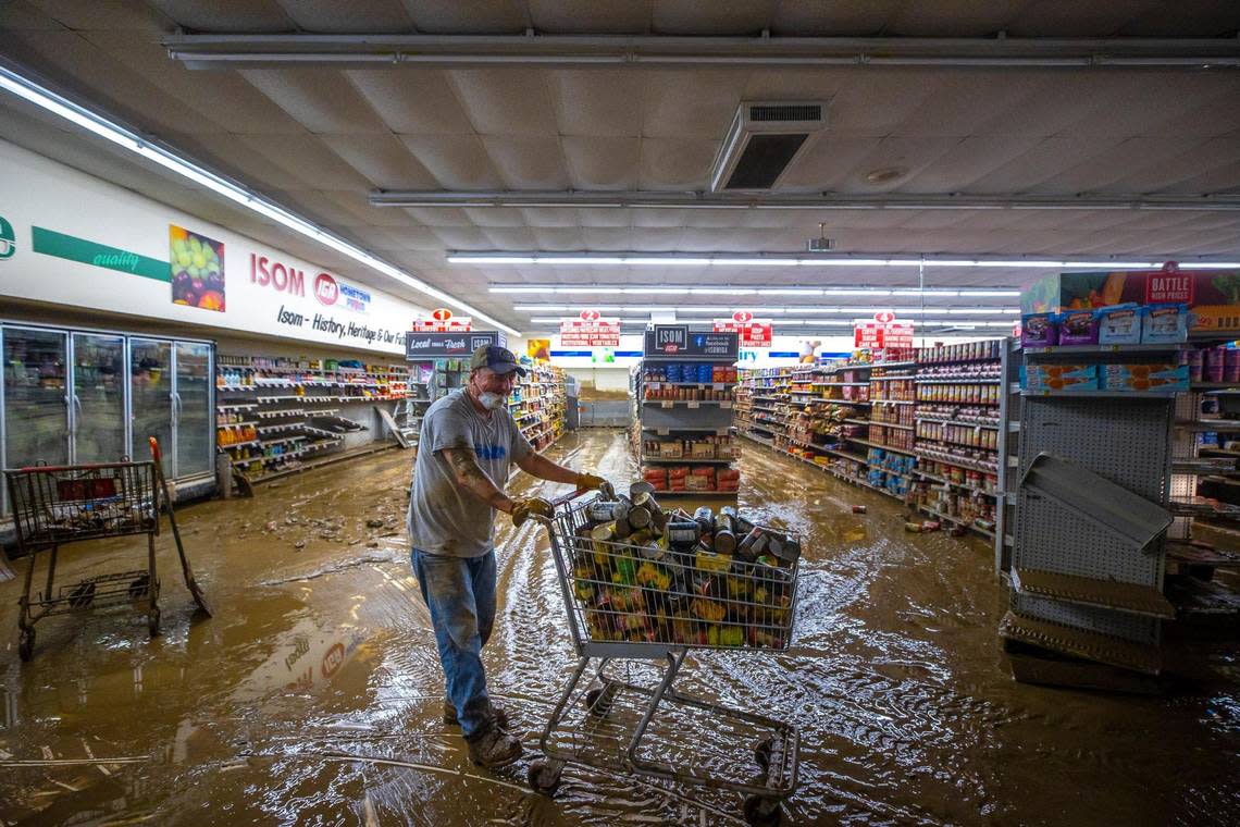 Dale Blair, an employee at Isom IGA in Isom, Ky., pushes a cart full of canned goods to be thrown out on Monday, Aug. 1, 2022. Historic floods last week ravaged the store, spoiling its inventory.