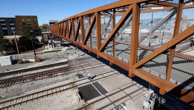A pedestrian crosses train tracks under a new pedestrian bridge at 300 North and 490 West, that crosses two Utah Transit Authority and three Union Pacific rail lines, in Salt Lake City on Wednesday, Oct. 18, 2023. The crossing is on a route heavily used by West High School students walking to and from school.