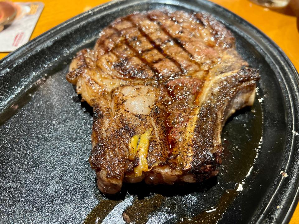 Ribeye steak on a black plate with juices leaking out at Outback Steakhouse