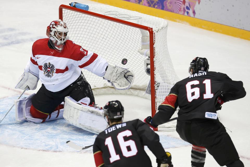 Austria's goalie Bernhard Starkbaum makes a save while Canada's Jonathan Toews and Rick Nash wait for the rebound during the first period of their men's preliminary round ice hockey game at the 2014 Sochi Winter Olympics, February 14, 2014. REUTERS/Jim Young (RUSSIA - Tags: OLYMPICS SPORT ICE HOCKEY)