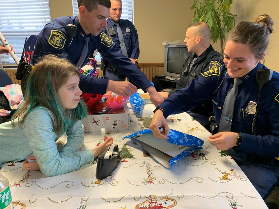 Nine-year-old Summer Lahaie wraps gifts with Michigan State Police troopers on Wednesday, Nov. 30.