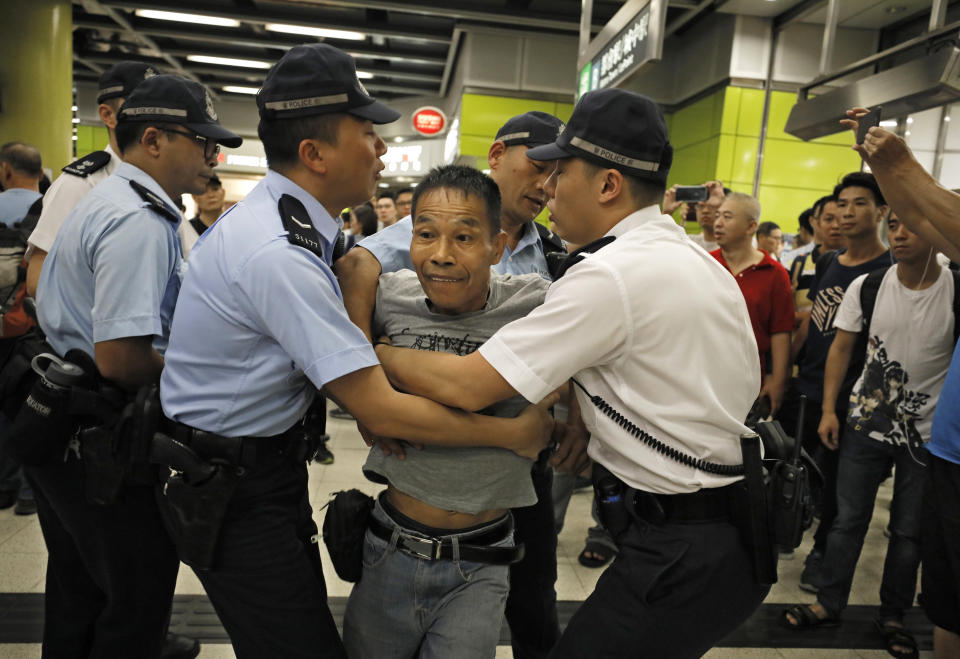 Police restrain an angry passenger who tried to fight with protesters in Hong Kong on Tuesday, July 30, 2019. Protesters in Hong Kong have disrupted subway service during the morning commute by blocking the doors on trains, preventing them from leaving the stations. (AP Photo/Vincent Yu)