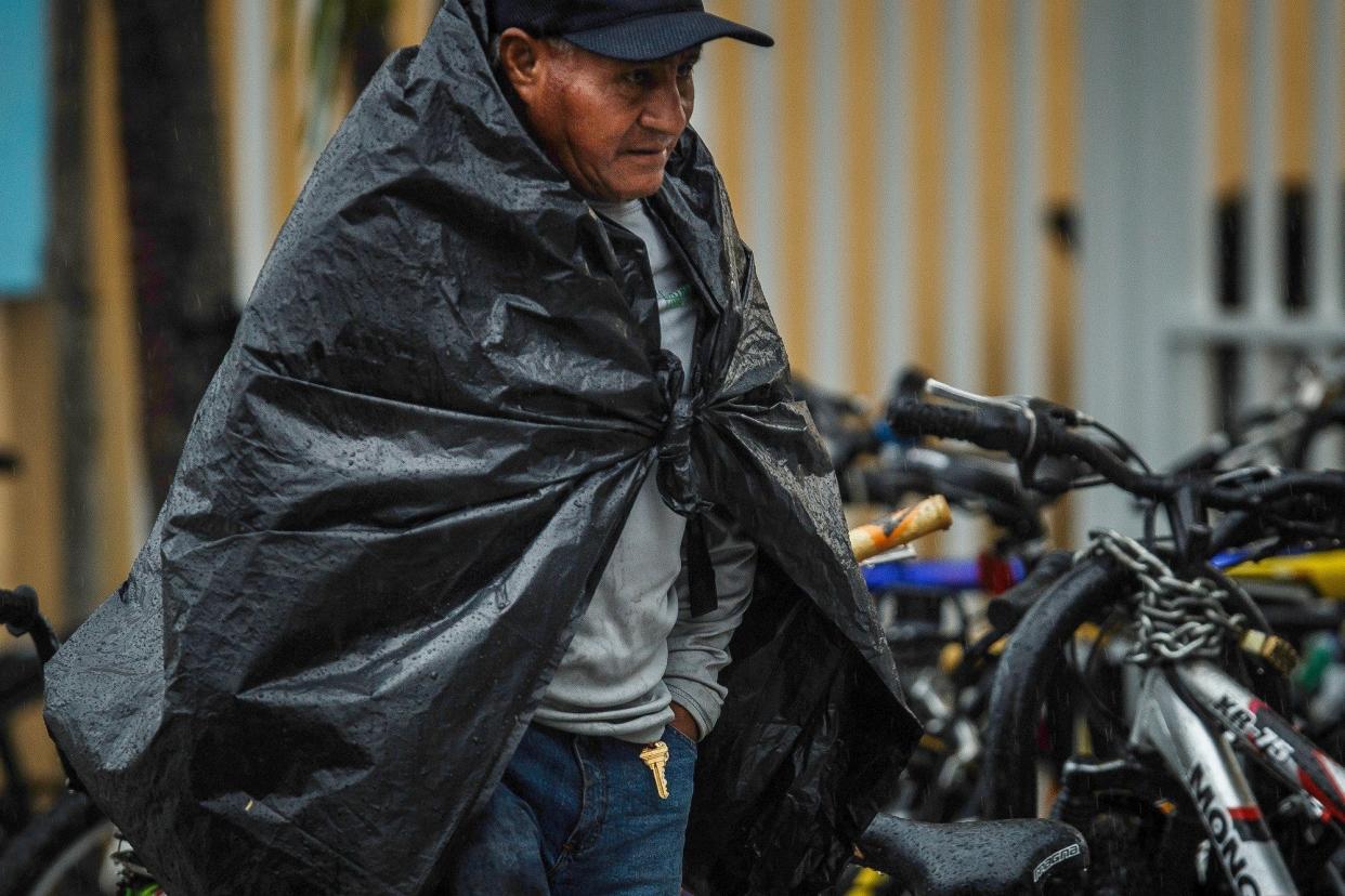 A man walks along Lake Avenue as an afternoon deluge from northeasterly storm clouds swamped the Dixie Highway corridor Tuesday in Lake Worth Beach.