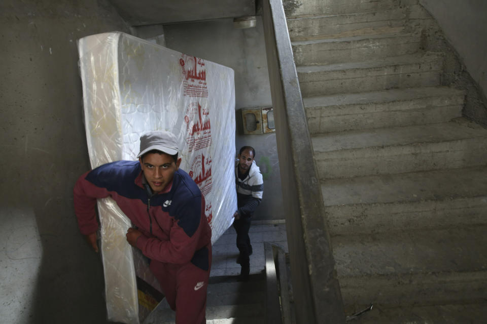 In this April 21, 2019 photo, Palestinian groom Yehiya Taleb, center, move a mattress, part of his wedding furniture, to his apartment in Shati refugee camp, Gaza City. Hundreds of young men in the Gaza Strip have turned to a small industry of lenders to help them pay for their weddings. Taleb got a job working as a waiter at a cafe earning about $180 a month, but that amount was not enough to cover wedding expenses so he took out a $2,000 package through the Farha Project, one of the wedding financing companies. (AP Photo/Adel Hana)