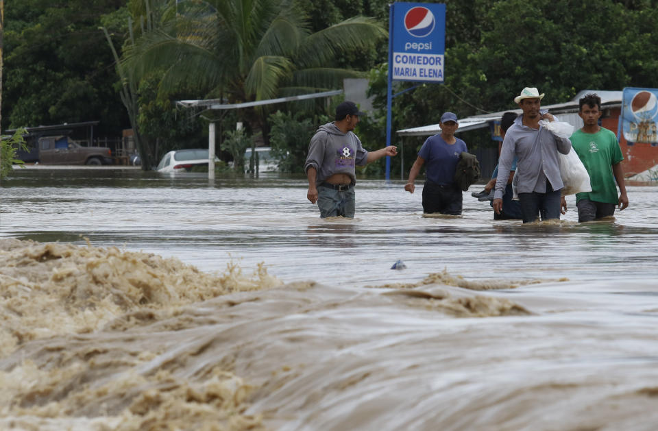 Men wade through a street flooded after the passing of Hurricane Iota in La Lima, Honduras, Wednesday, Nov. 18, 2020. Iota flooded stretches of Honduras still underwater from Hurricane Eta, after it hit Nicaragua Monday evening as a Category 4 hurricane and weakened as it moved across Central America, dissipating over El Salvador early Wednesday. (AP Photo/Delmer Martinez)