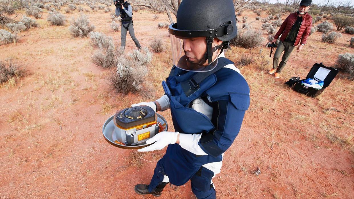 Ein Wissenschaftler hält in der Wüste des Woomera-Testgeländes für Luft- und Raumfahrt im Süden Australiens die Probenkapsel der japanischen Raumsonde «Hayabusa2».