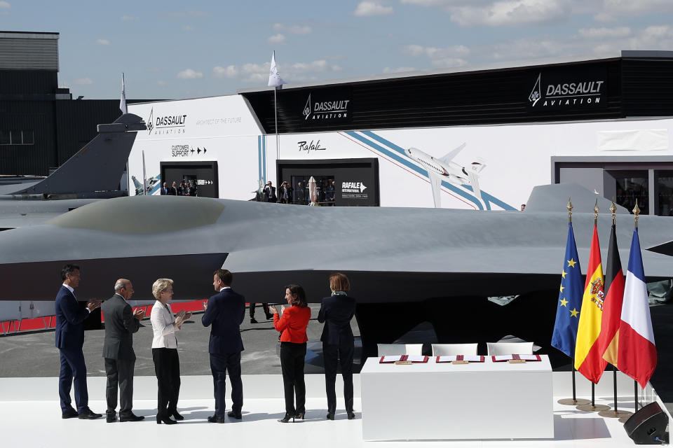 Airbus Defence and Space Chief Executive Officer Dirk Hoke, left, Dassault Aviation Chairman and CEO Eric Trappier, second left, German Defense Minister Ursula von der Leyen, third left, French President Emmanuel Macron, Spanish Defense Minister Margarita Robles, second right, and French Defense Minister Florence Parly attend the unveiling of the French-German-Spanish new generation fighter model during a visit the Paris Air Show in Le Bourget Airport near Paris, France, Monday June 17, 2019. (Yoan Valat/Pool via AP)