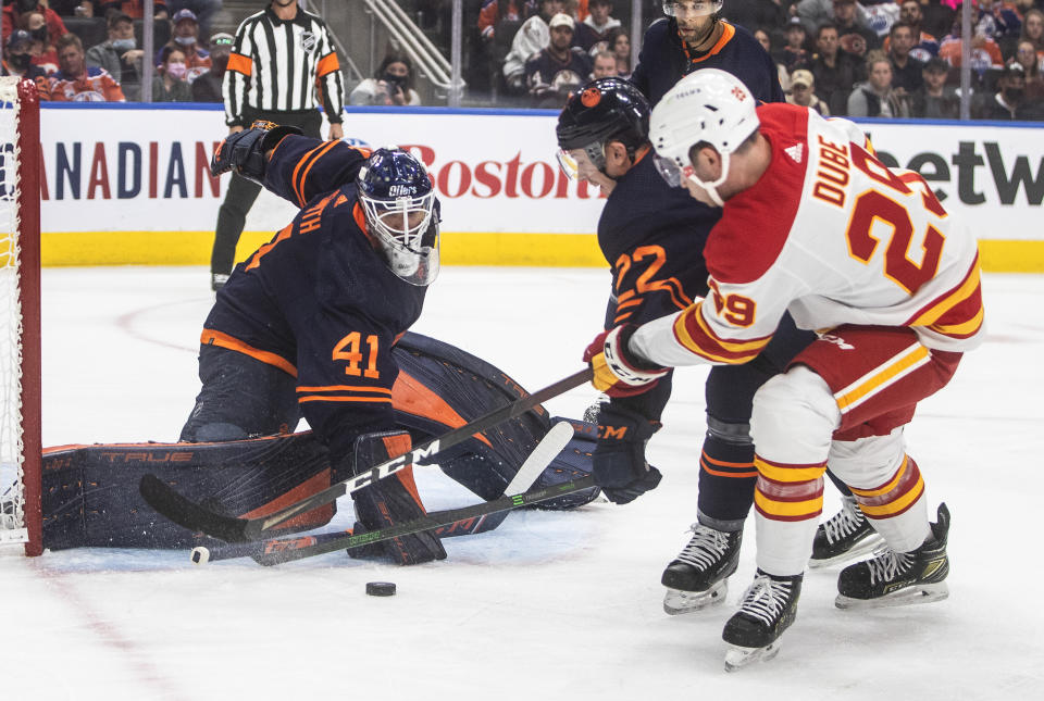 Calgary Flames' Dillon Dube (29) is stopped by Edmonton Oilers goalie Mike Smith (41) as Tyson Barrie (22) defends during the first period of an NHL hockey game Saturday, Oct. 16, 2021, in Edmonton, Alberta. (Jason Franson/The Canadian Press via AP)