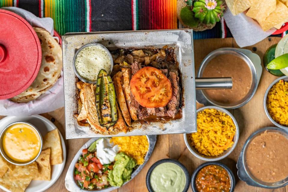 El Tiempo Cantina’s steak and chicken fajita dish, with rice, refried beans, guacamole, pico de gaillo, and queso sides.