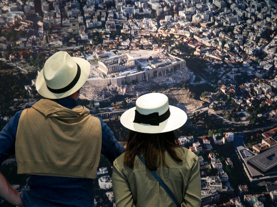 Visitors look at a photo of ancient Greece at a museum.