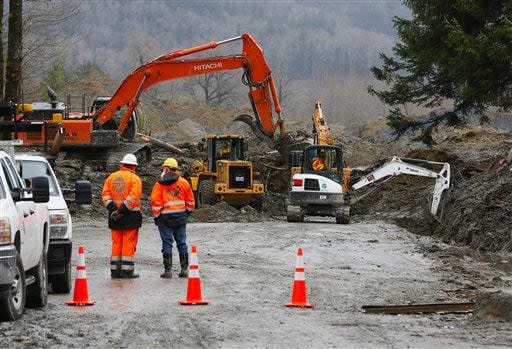 Washington State Department of Transportation workers observe the scene as crews work at the west side of the mudslide on Highway 530 near mile marker 37 in Arlington, Wash.,  on Sunday, March 30, 2014. Periods of rain and wind have hampered efforts the past two days, with some rain showers continuing today. Last night, the confirmed fatalities list was updated to 18, with the number of those missing falling from 90 to 30. (AP Photo/Rick Wilking, Pool)