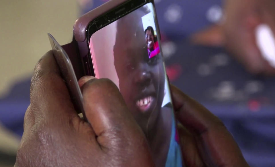 In this image taken from video, Cecilia Oyet, whose daughter is a medical student at Wuhan University of Science and Technology, holds the phone at the house of fellow parent Margaret Ntale, whose three student daughters are stranded in Wuhan, as they speak by video-call to their children and other Ugandan students who are stranded in Wuhan, in Kampala, Uganda on Thursday, Feb. 27, 2020. Parents' fears are growing for the thousands of African students who are thought to be stranded in China's locked-down city of Wuhan amid the virus outbreak, with concerns that students are running out of food and money weeks after other countries evacuated citizens. (AP Photo)