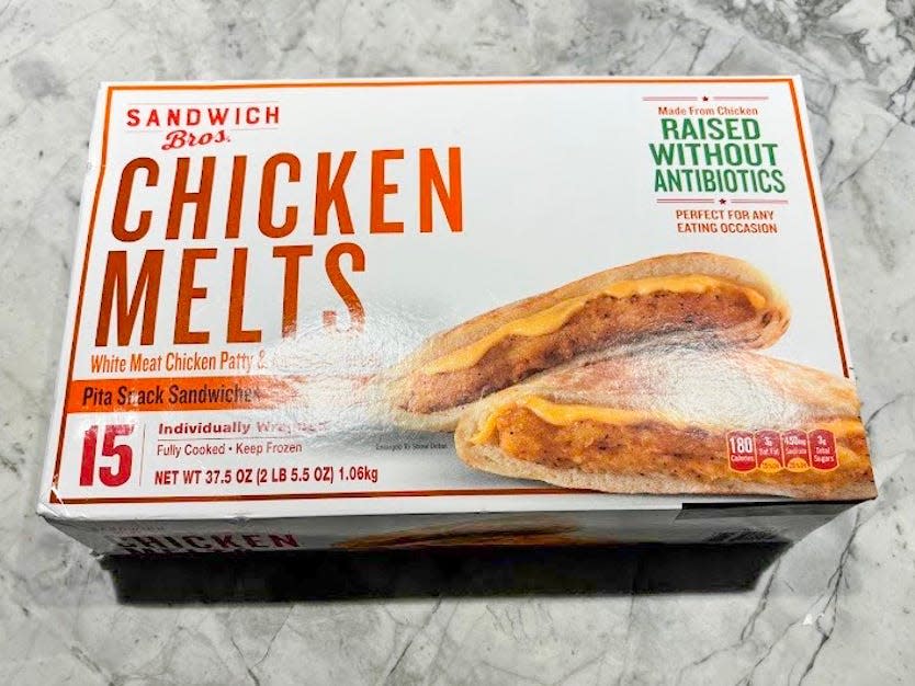 A white box of chicken melts, with an image of pita sandwiches on the box, on a gray table