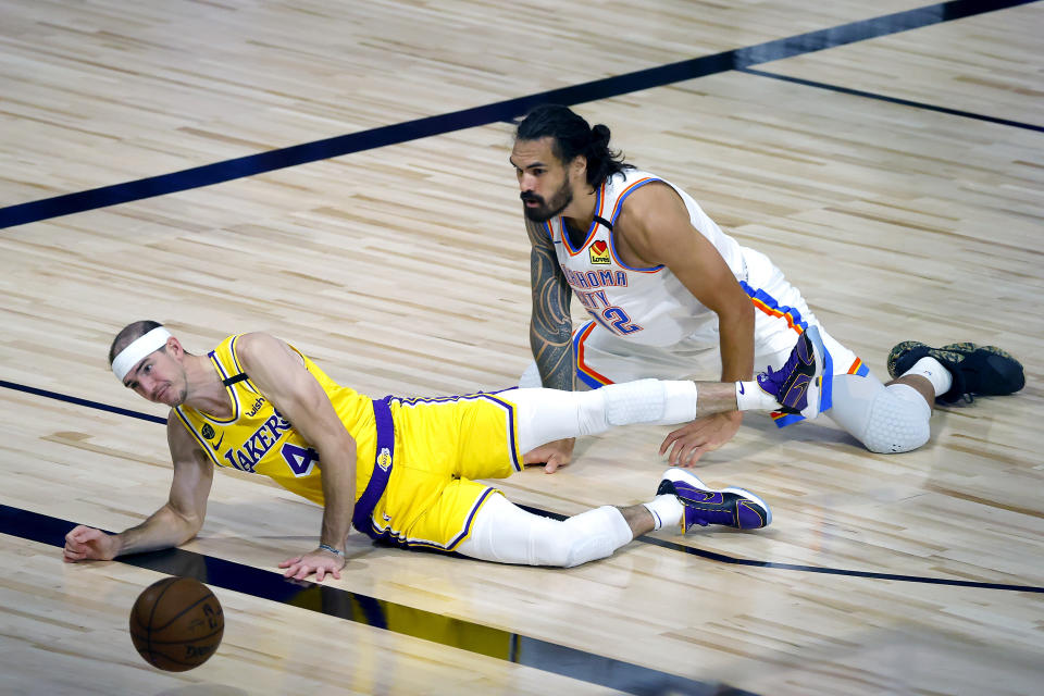 Alex Caruso, left, of the Los Angeles Lakers attempts to steal the ball from Steven Adams, right, of the Oklahoma City Thunder during the second half of an NBA basketball game Wednesday, Aug. 5, 2020, in Lake Buena Vista, Fla. (Kevin C. Cox/Pool Photo via AP)