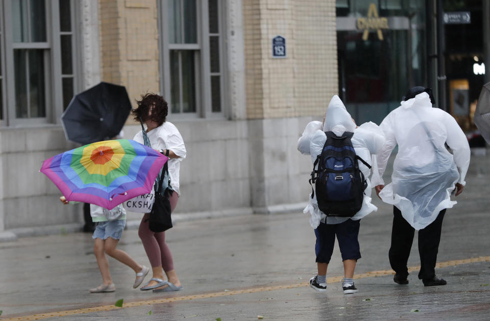 A mother and her daughter hold an umbrella against the strong wind and rain caused by Typhoon Lingling in Seoul, South Korea, Saturday, Sept. 7, 2019. A typhoon passed along South Korea's coast Saturday, toppling trees, grounding planes and causing at least two deaths before the storm system made landfall in North Korea. (AP Photo/Ahn Young-joon)
