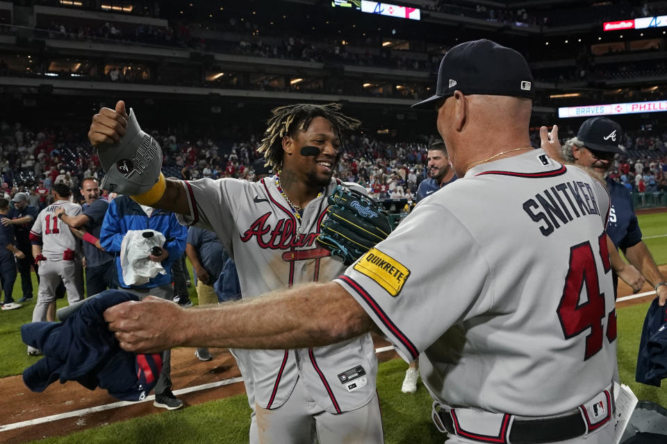 Atlanta Braves' Ronald Acuna Jr., left, and Brian Snitker celebrate after clinching their sixth consecutive NL East title by defeating the Philadelphia Phillies in a baseball game, Wednesday, Sept. 13, 2023, in Philadelphia. (AP Photo/Matt Slocum)