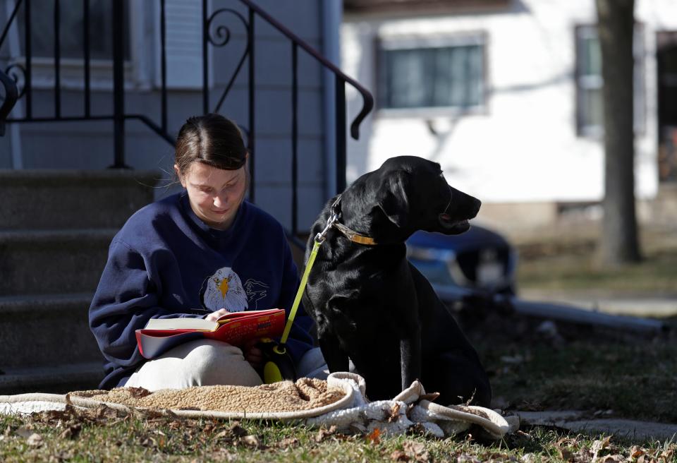 Britany Mueller enjoys unseasonably warm temperatures reading a book and spending time with her dog Dixie in March in Appleton.