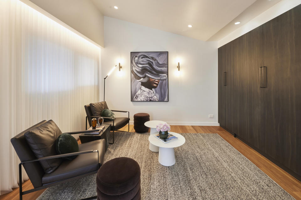 Two black leather chairs on the left, white tables in the middle and brown wall of cupboards on the right. 