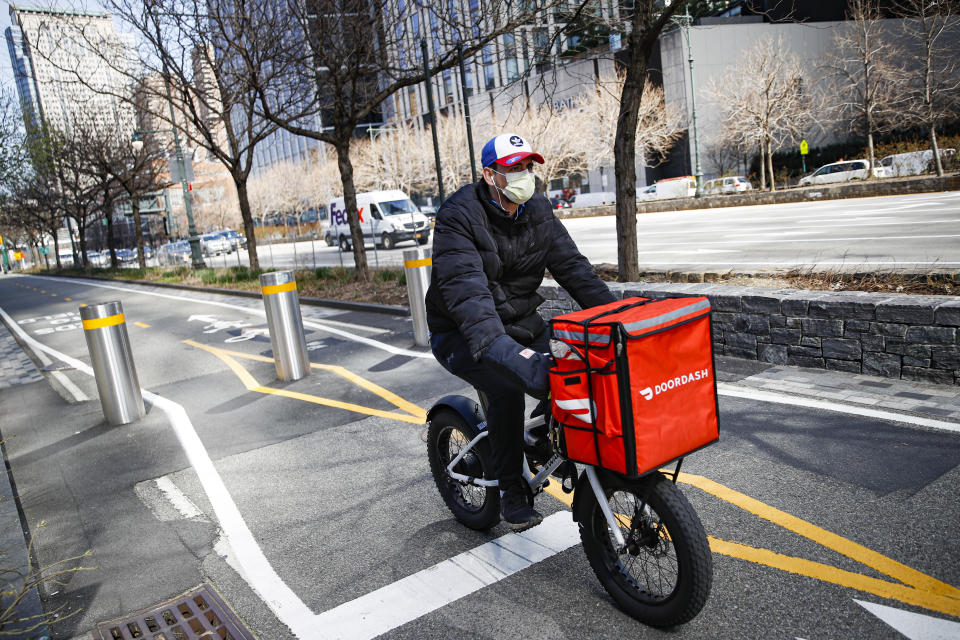 FILE - In this March 16, 2020 file photo, a delivery worker rides his bicycle along a path on the West Side Highway in New York. U.S. demand for grocery delivery is cooling as food prices rise. Some shoppers are shifting to less expensive grocery pickup, while others are returning to the store. (AP Photo/John Minchillo, File)