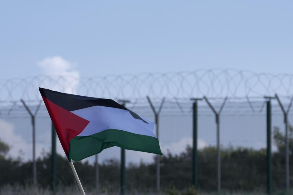 A Demonstrator holds a Palestinian's flag flag during a protest, condemning Israel's military operations inside the Gaza strip, outside the entrance of RAF Akrotiri, near southern port city of Limassol, Cyprus, on Sunday, Jan. 14, 2024. Protest organizers said the protest also condemns what they call the "use of Cyprus as a launchpad for war" after British warplanes took off from RAF Akrotiri to bomb targets in Yemen following Houthi attacks on international shipping. (AP Photo/Petros Karadjias)