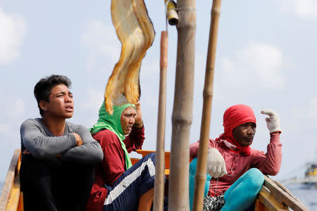 Philippine fishermen watch a nearby China Coast Guard ship patrolling at the disputed Scarborough Shoal April 6, 2017. Picture taken April 6, 2017. REUTERS/Erik De Castro