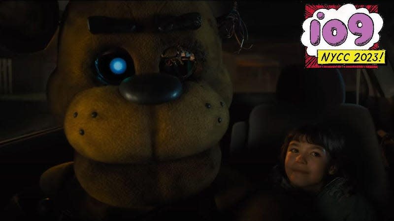 A screenshot from the Five Nights at Freddy's movie with the animatronic sitting next to a girl.