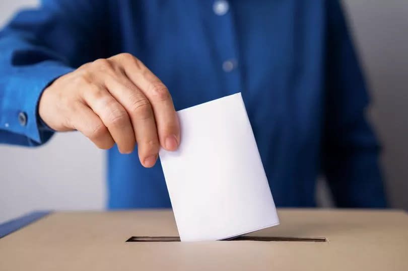 Man putting voting slip through top of ballot box