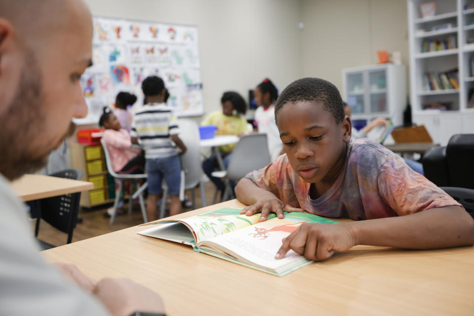 Michael Crowder, 11, right, reads to Tim McNeeley, left, during an after-school literacy program in Atlanta on Thursday, April 6, 2023. McNeeley, director of the Atlanta based Pure Hope Project, hosts the daily program for children in kindergarten through fifth grade. (AP Photo/Alex Slitz)
