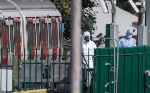 Forensics officers, one is a gas mask (L) can be seen next to the evacuated tube train - Credit: Peter Macdiarmid/LNP