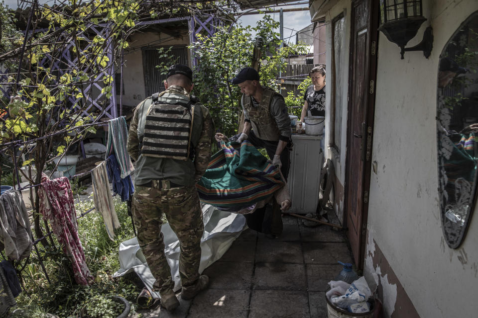 La policía ucraniana retira el cuerpo de una mujer de 65 años de su casa en Lysychansk, al otro lado del río Síverski Donets desde Severodonetsk, Ucrania, el martes 24 de mayo de 2022. (Finbarr O'Reilly/The New York Times)
