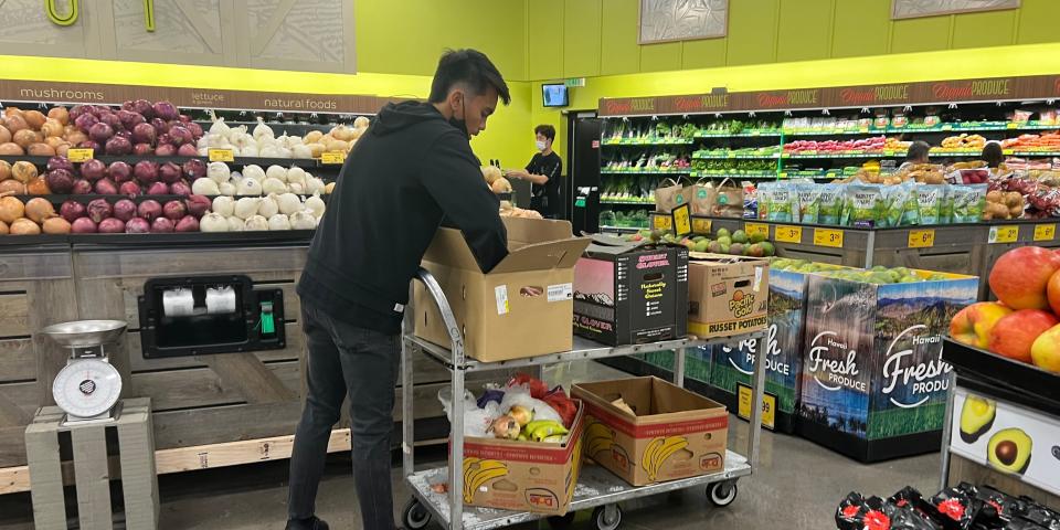 Grocery store worker stocking produce at Foodland.