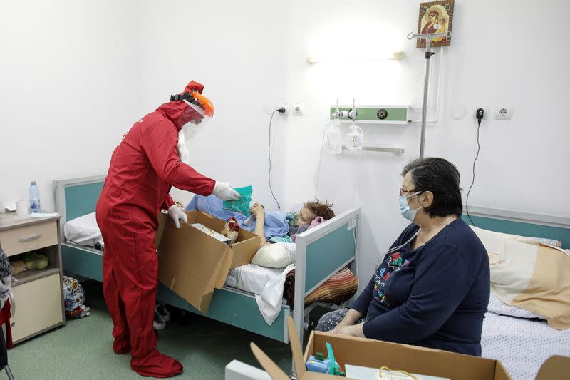 Ionut Ivan, a 40-year-old nurse, dressed in red Personal Protective Equipment (PPE) opens a box with sweets and fruits for one of the patients, in Bucharest