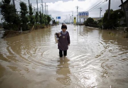 A local resident wades through a residential area flooded by the Kinugawa river, caused by typhoon Etau, in Joso, Ibaraki prefecture, Japan, September 11, 2015. REUTERS/Issei Kato