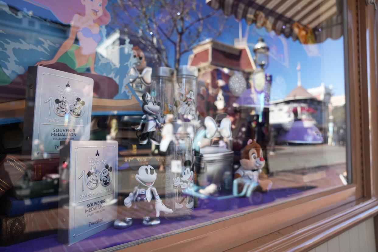 Pieces from the platinum-infused Disney100 merchandise collection are seen through a window along Disneyland's Main Street, U.S.A.