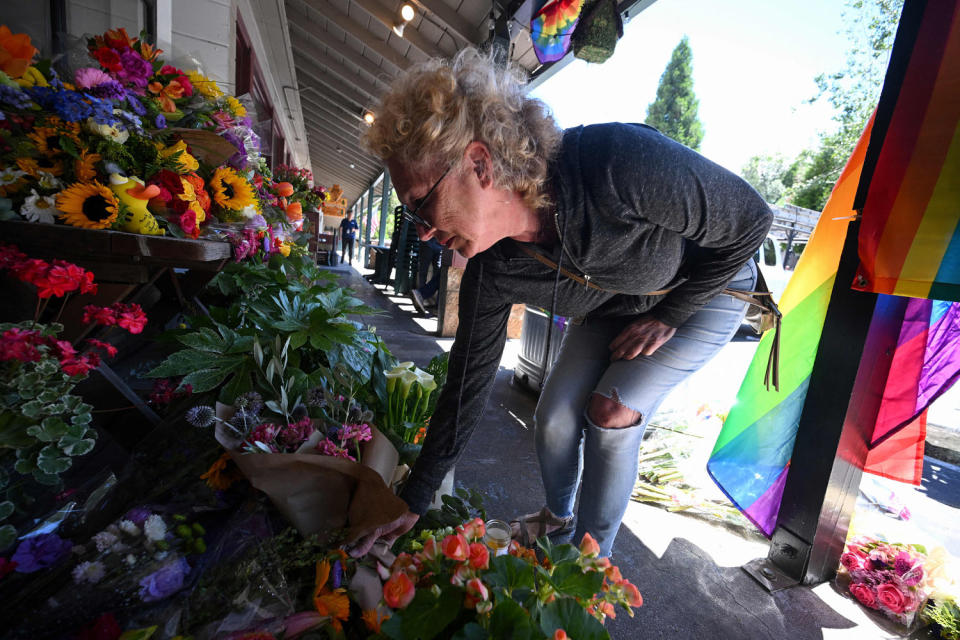 A resident leaves flowers at a makeshift memorial outside the Mag.Pi clothing store (Robyn Beck / AFP via Getty Images)