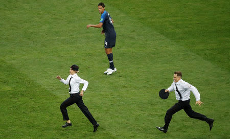 Soccer Football - World Cup - Final - France v Croatia - Luzhniki Stadium, Moscow, Russia - July 15, 2018 Pitch invaders run on the pitch during the match as France's Raphael Varane looks on REUTERS/Christian Hartmann