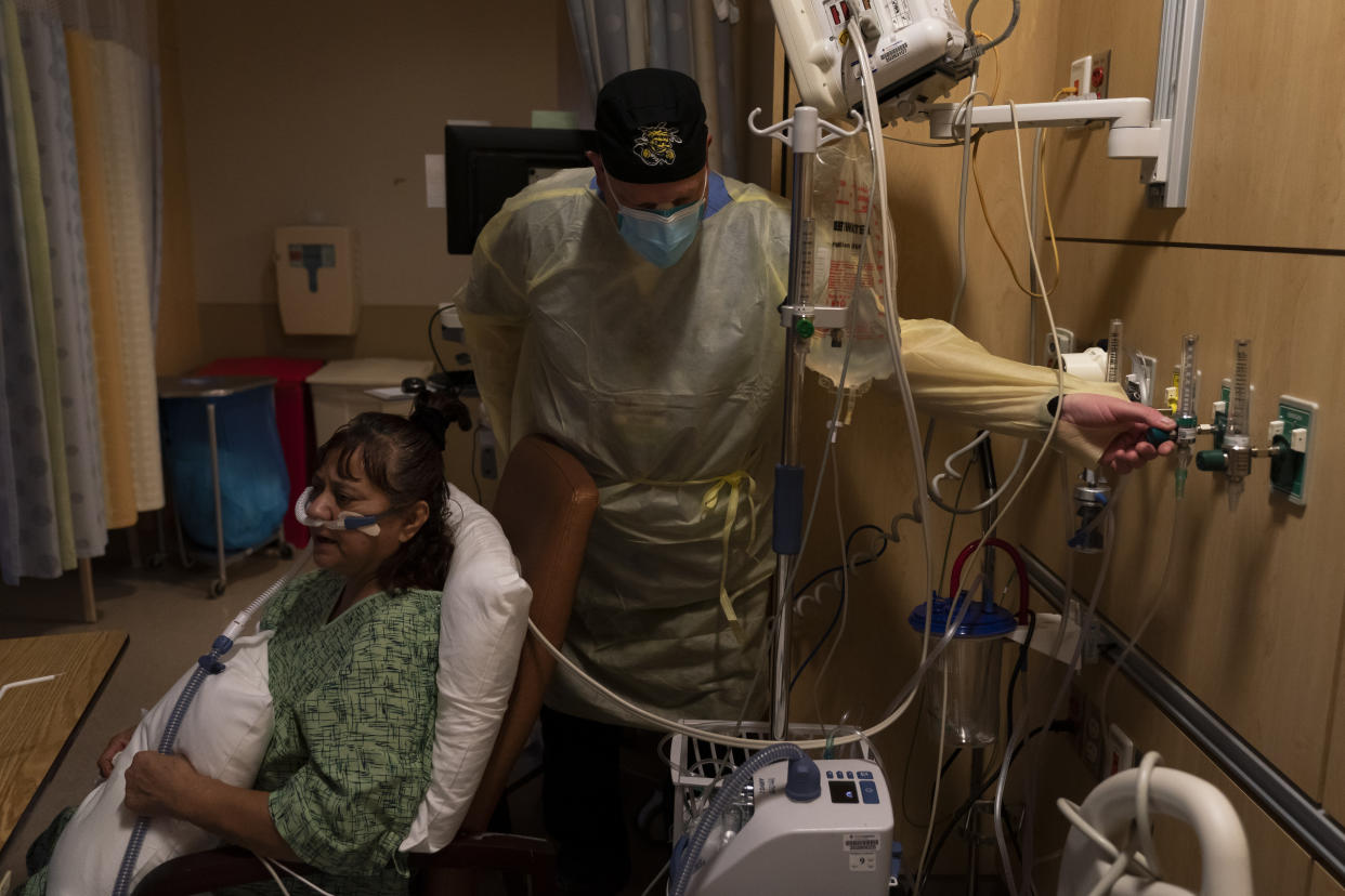 Respiratory therapist Frans Oudenaar adjusts the oxygen flow rate for Linda Calderon, 71, in a COVID-19 unit at Providence Holy Cross Medical Center in Los Angeles, Tuesday, Dec. 14, 2021. (AP Photo/Jae C. Hong)